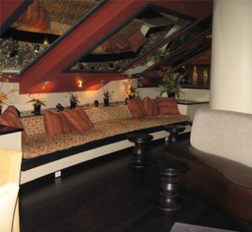 Cozy attic lounge with cushioned seating and warm lighting.