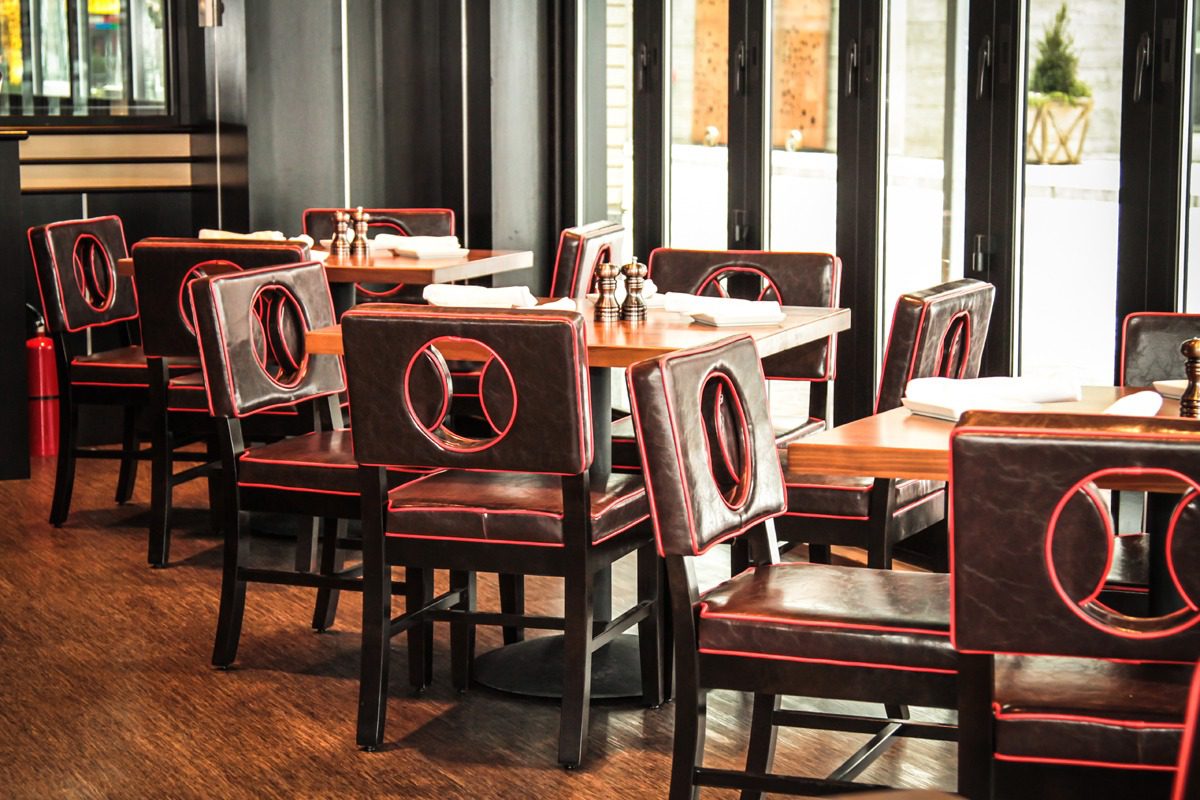 Empty wooden chairs and tables in a cozy restaurant with natural light.