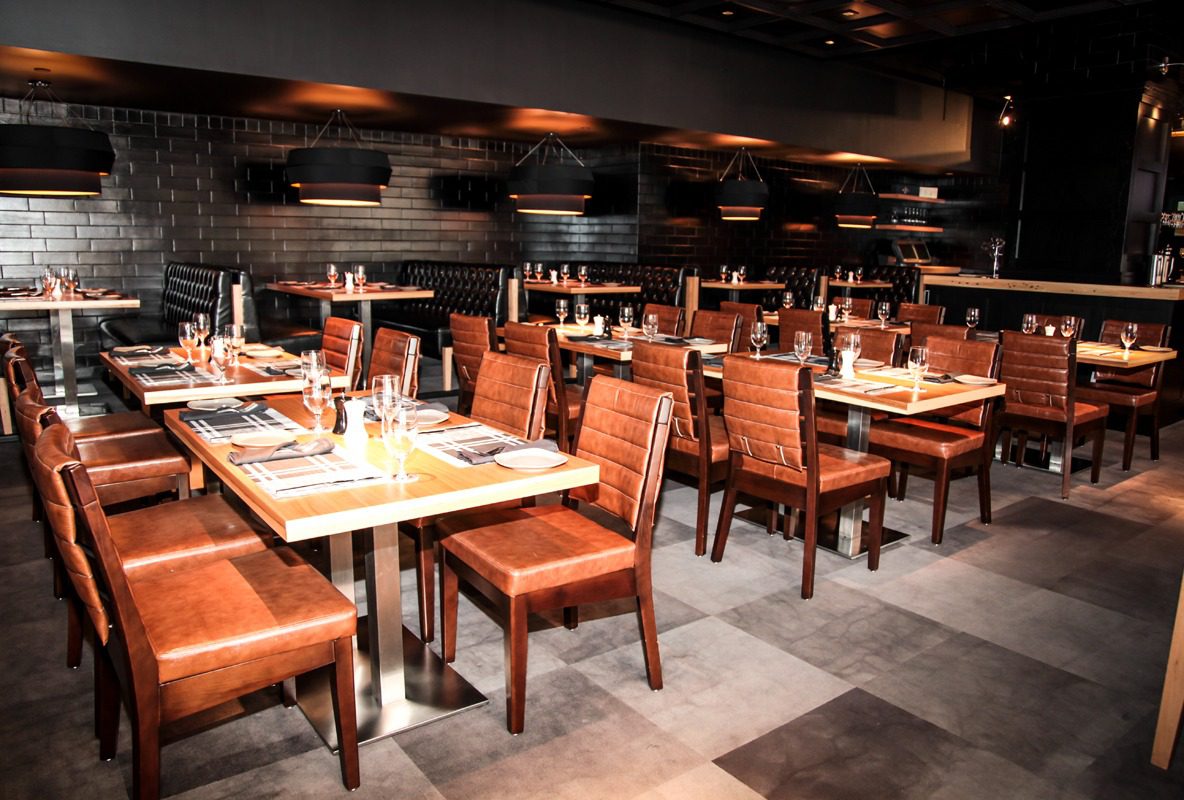 Elegant restaurant dining area with wooden chairs and set tables.