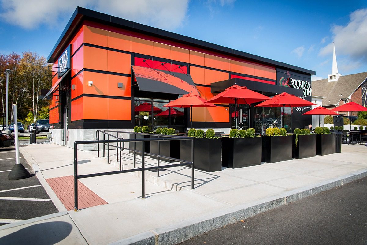 Modern restaurant exterior with bright orange accents and outdoor seating.