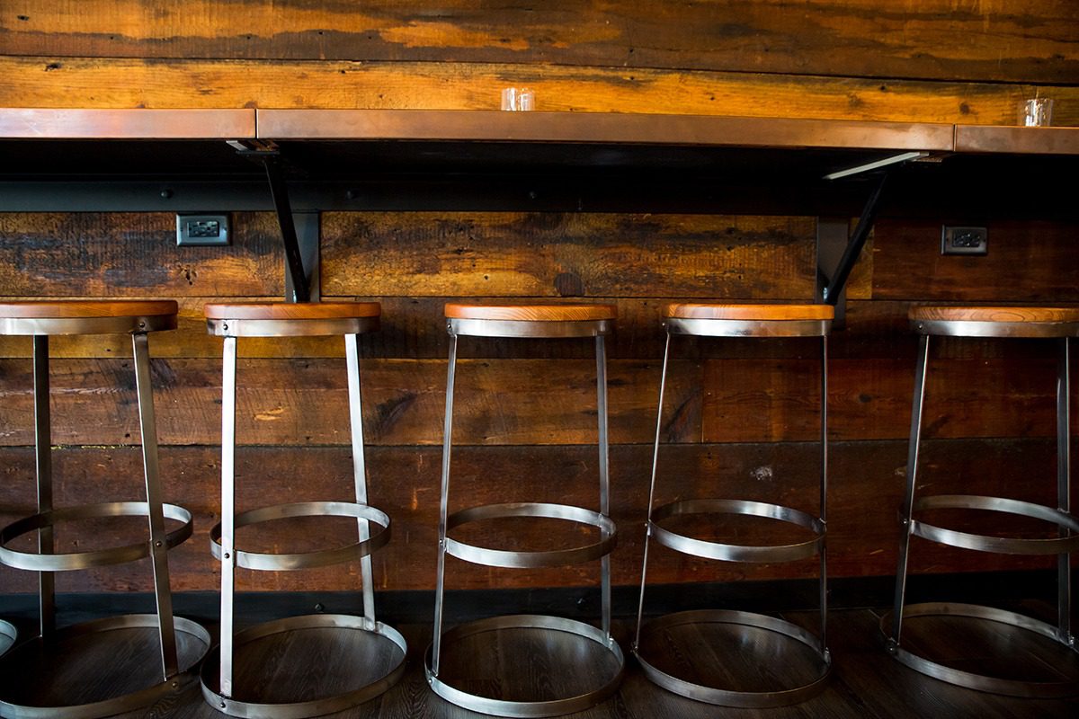 Empty transparent bar stools lined up under a wooden counter.