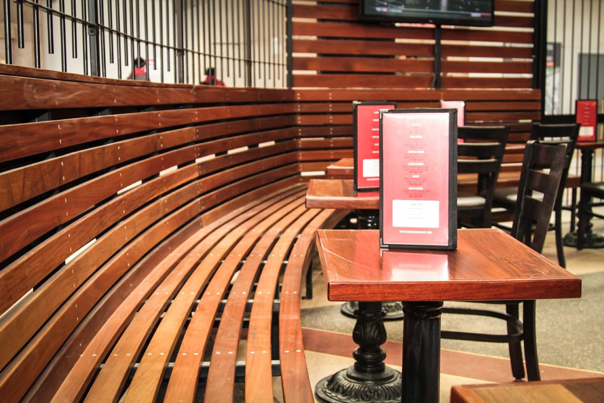 Curved wooden benches surround a small table with a menu in a cozy, warm-lit setting.
