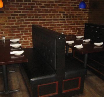 Cozy restaurant booths with brick walls and wooden floors.