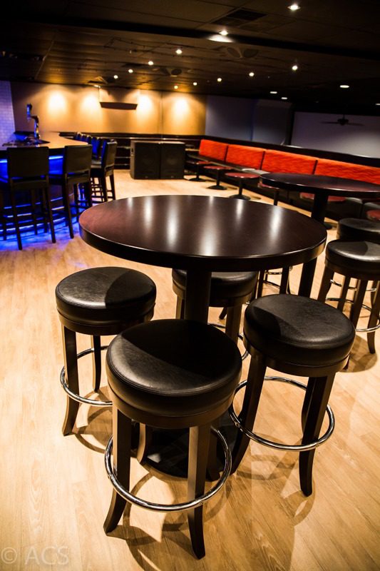 Cozy bar seating with round tables and cushioned stools.