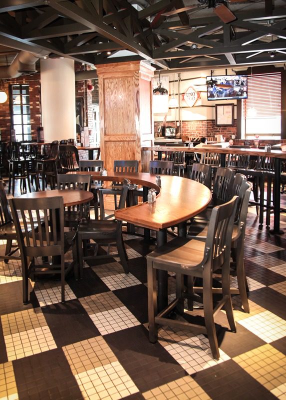 Empty rustic pub with wooden chairs and checkered floor.