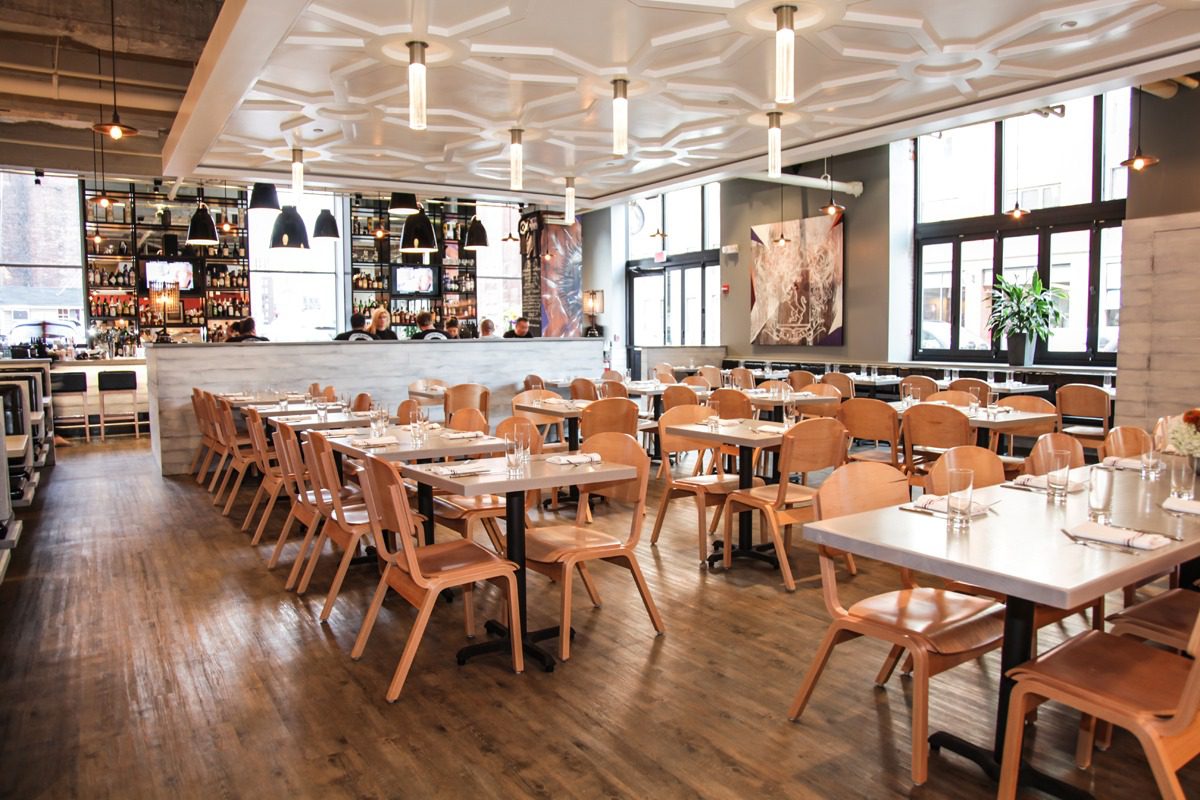 A modern, stylish restaurant with wooden furniture and ample natural light.