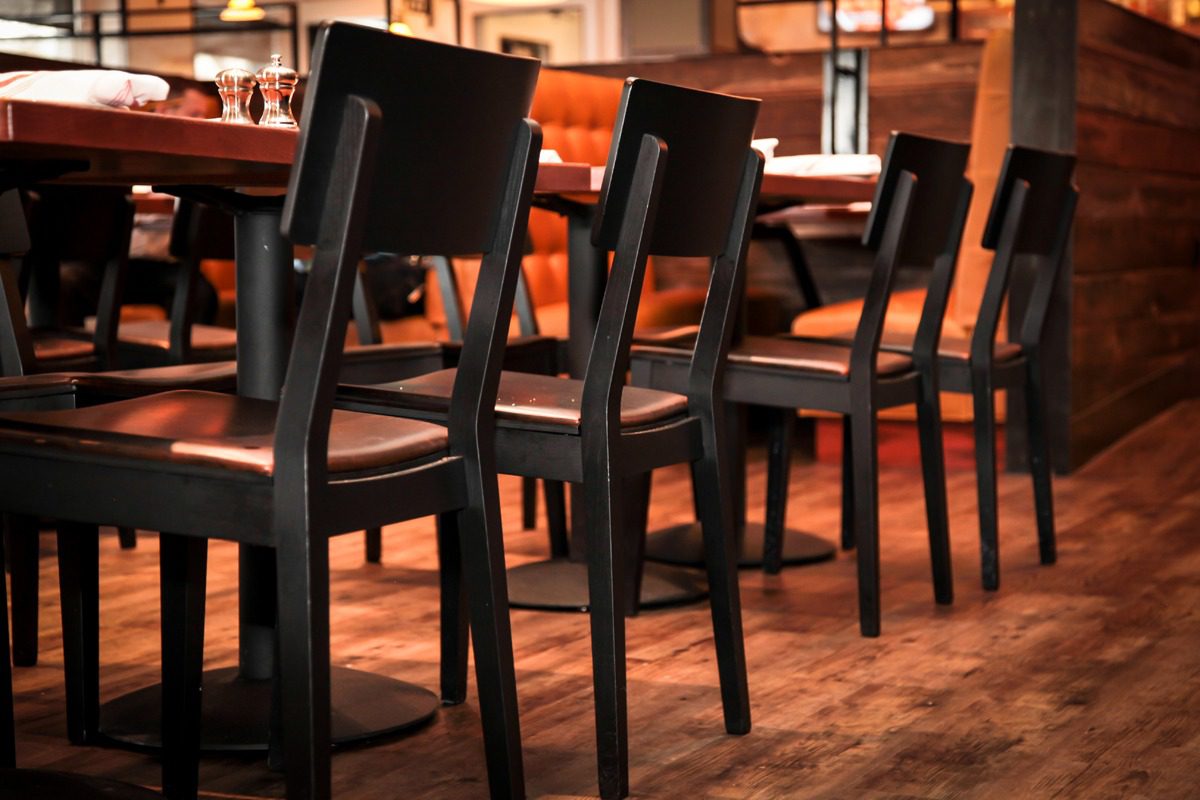 Row of black wooden chairs with cushioned seats in a cozy restaurant.