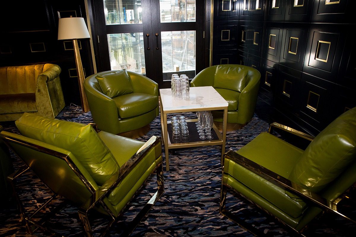 Cozy seating area with green leather chairs around a wooden table.