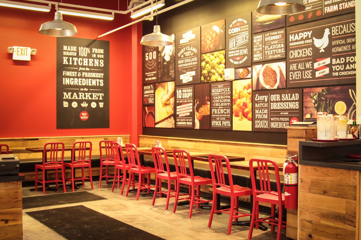 Cozy restaurant with red chairs and colorful menu boards on the wall.