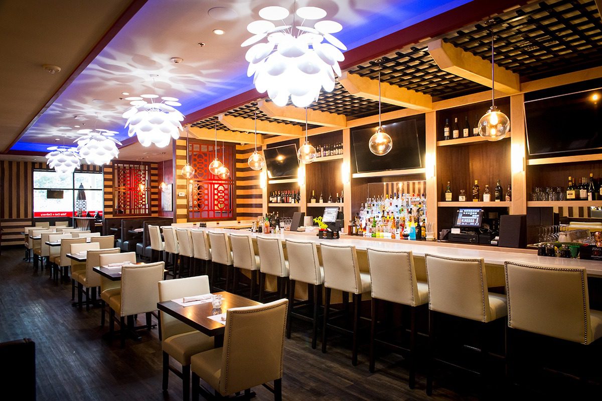 Elegant bar with modern lighting and white chairs.