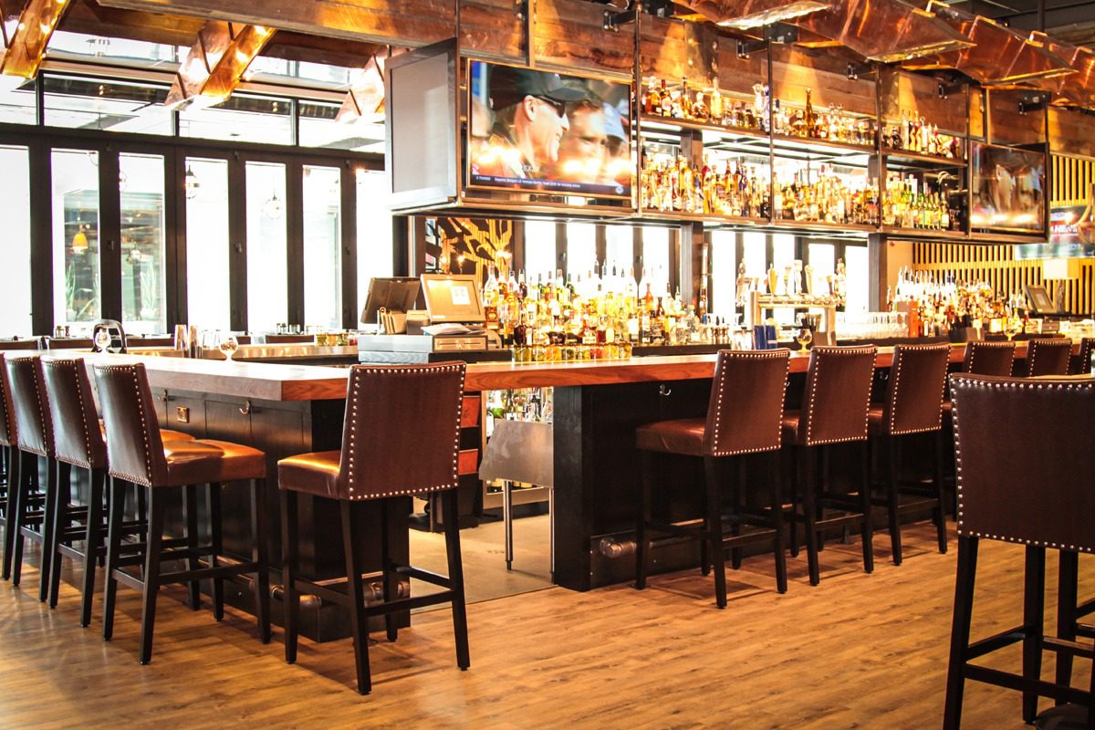 Elegant bar with wooden stools and warm lighting.