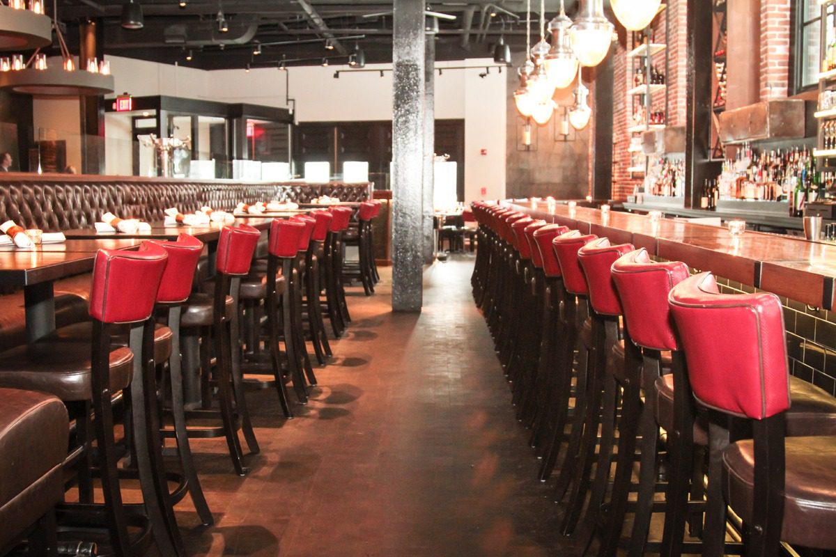 Elegant bar with red stools and warm lighting.