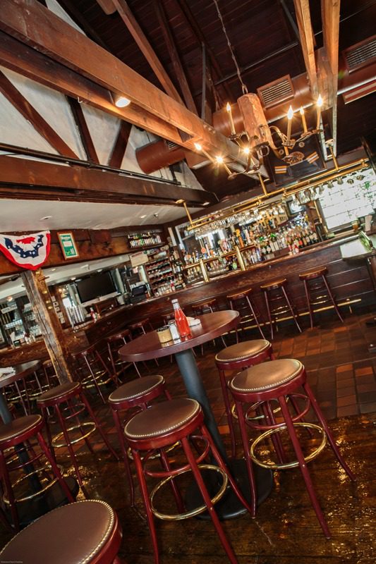Cozy rustic bar with wooden beams and stools.