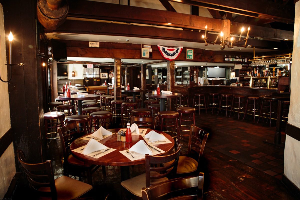 Cozy rustic bar with wooden tables and dim lighting.