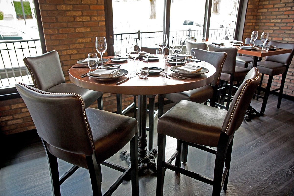 Cozy round dining table set with leather chairs and elegant tableware.