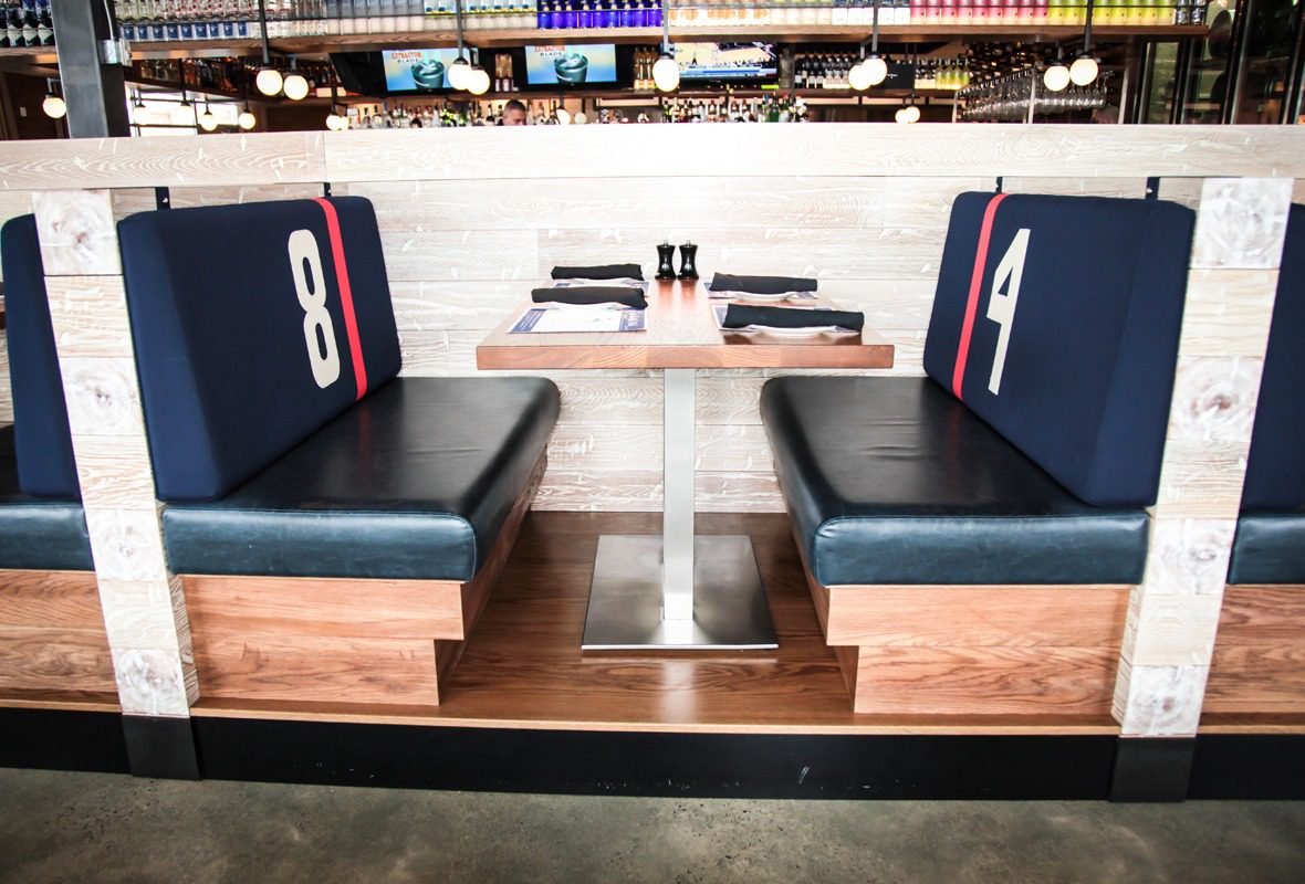 Empty diner booth seating with blue cushions and numbered backs.