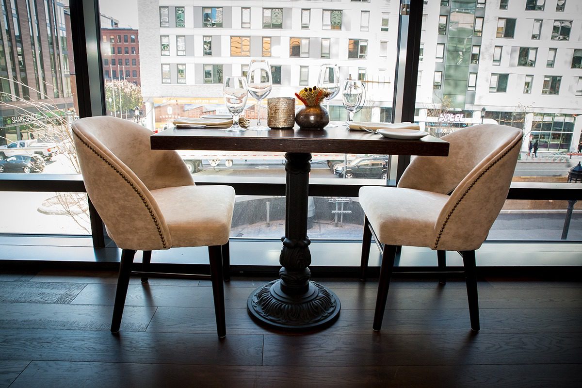 Cozy dining setup with two cushioned chairs and a round table by a large window.