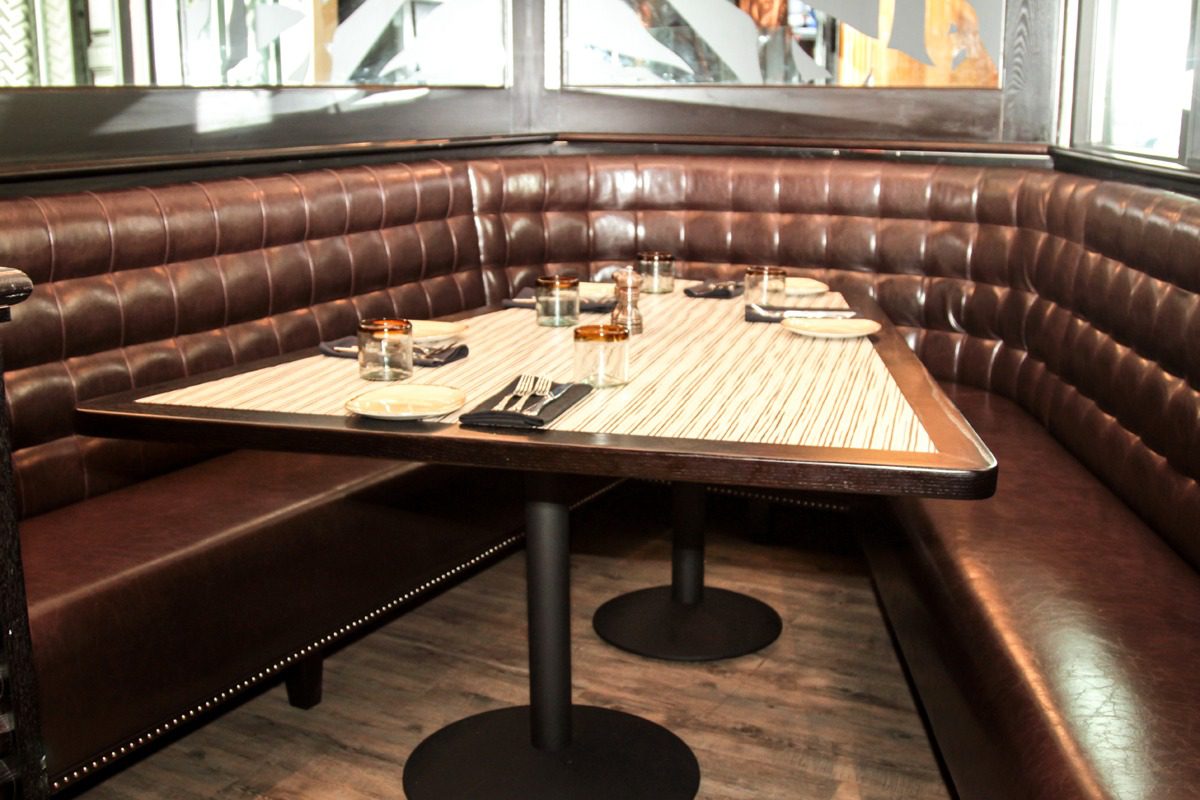 Cozy restaurant booth with neatly set tables and cushioned seating.