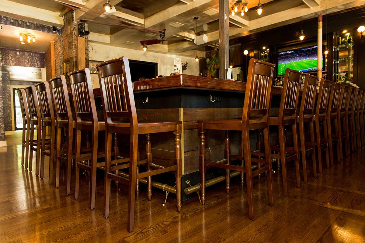 Rustic wooden bar table with high chairs in a cozy pub.