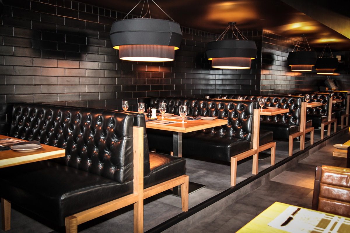 Cozy restaurant booths with tufted leather seats and wooden tables.