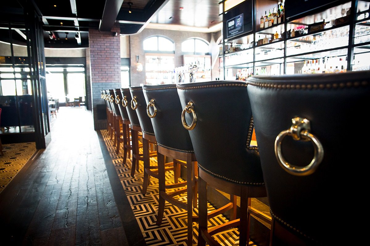 Row of leather bar stools with gold ring handles in a stylish bar.