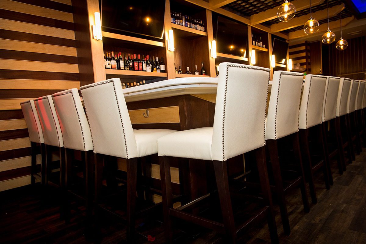 Elegant bar stools lined up at a polished wooden bar counter.