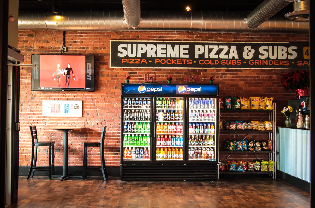 Interior of a pizza shop with drinks and snacks display.