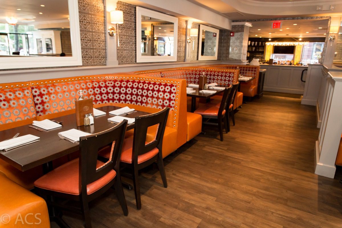 Cozy restaurant booth seating with orange upholstery and wooden chairs.