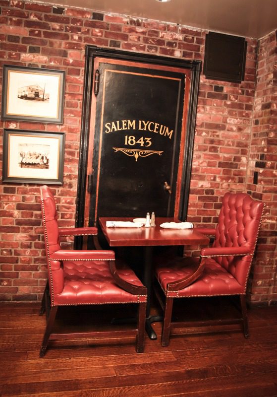 Cozy corner with red leather chairs and a table against a brick wall.