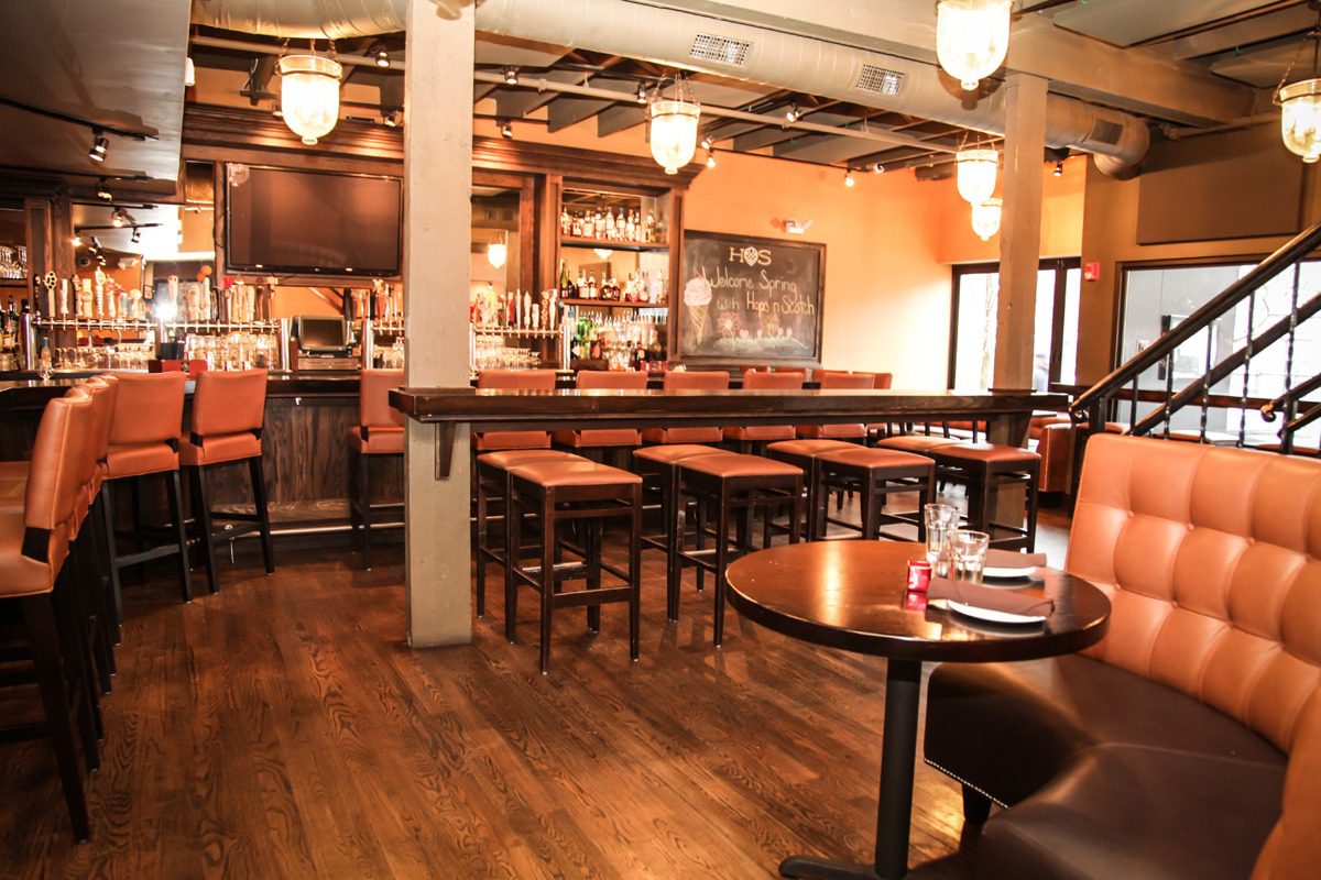 Cozy bar interior with wooden furniture and warm lighting.