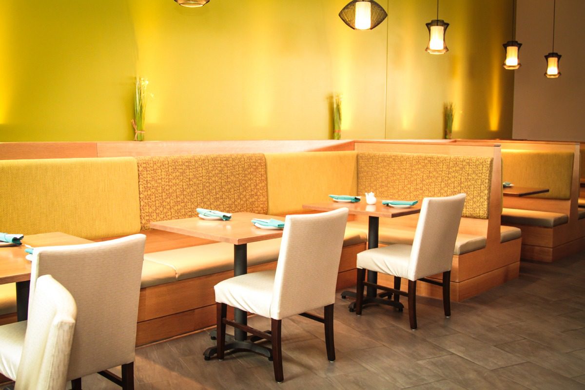 Bright yellow dining area with modern white chairs and cozy bench seating.