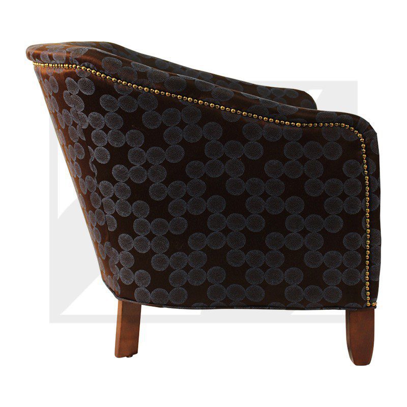 Side view of a dark patterned armchair with wooden legs.