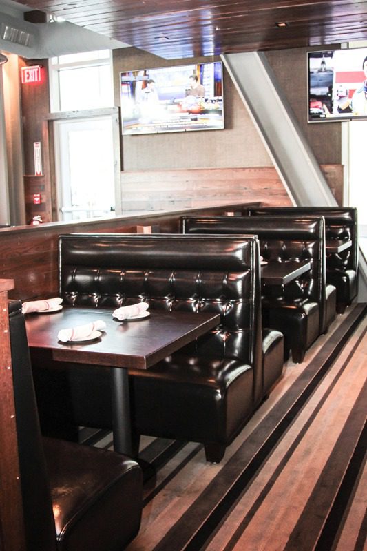 Cozy leather booths with wooden tables in a warm, inviting restaurant setting.