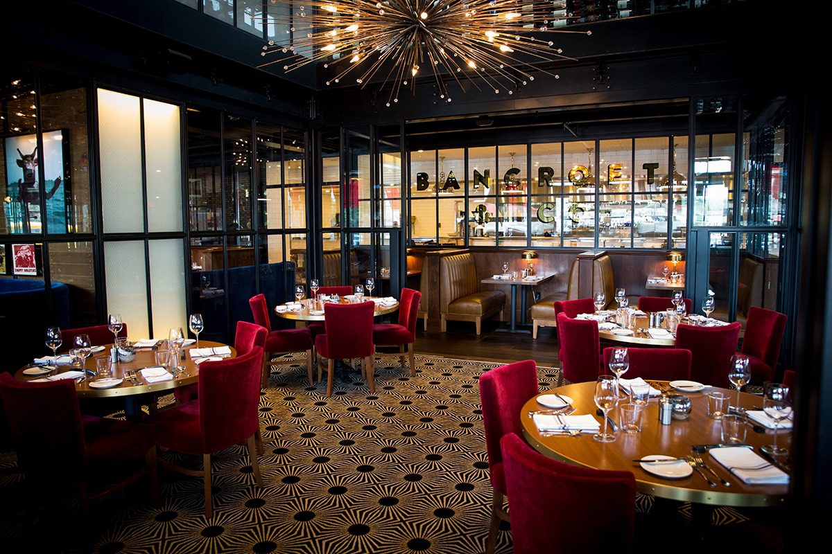 Elegant restaurant with red chairs and warm lighting.