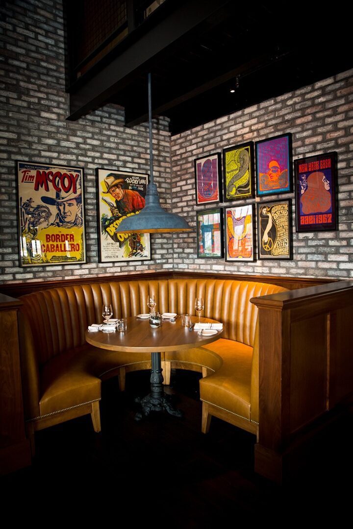 Cozy restaurant booth with artistic posters on exposed brick wall.