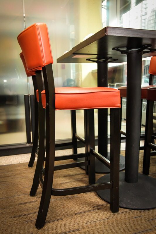 Red cushioned bar stools with dark wooden legs at a high table.