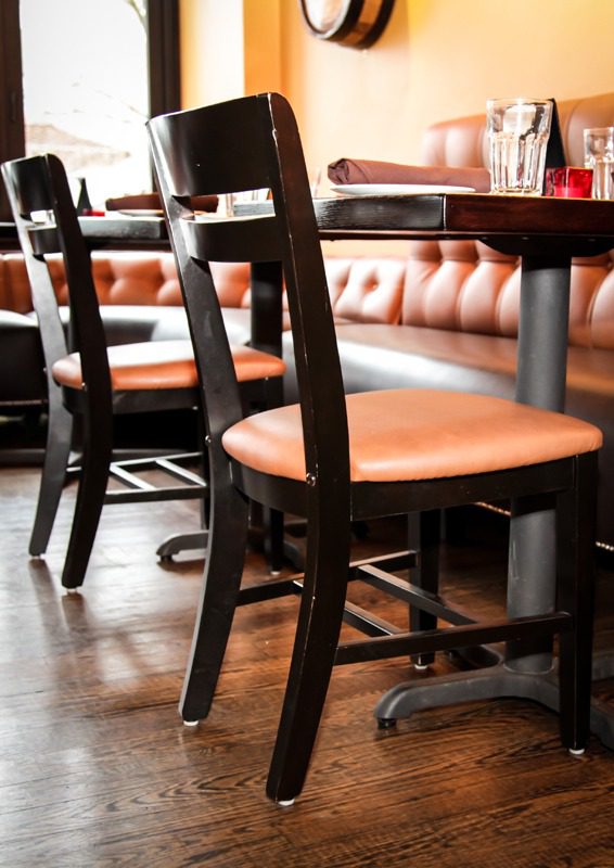 Wooden chairs with orange cushions in a cozy restaurant setting.