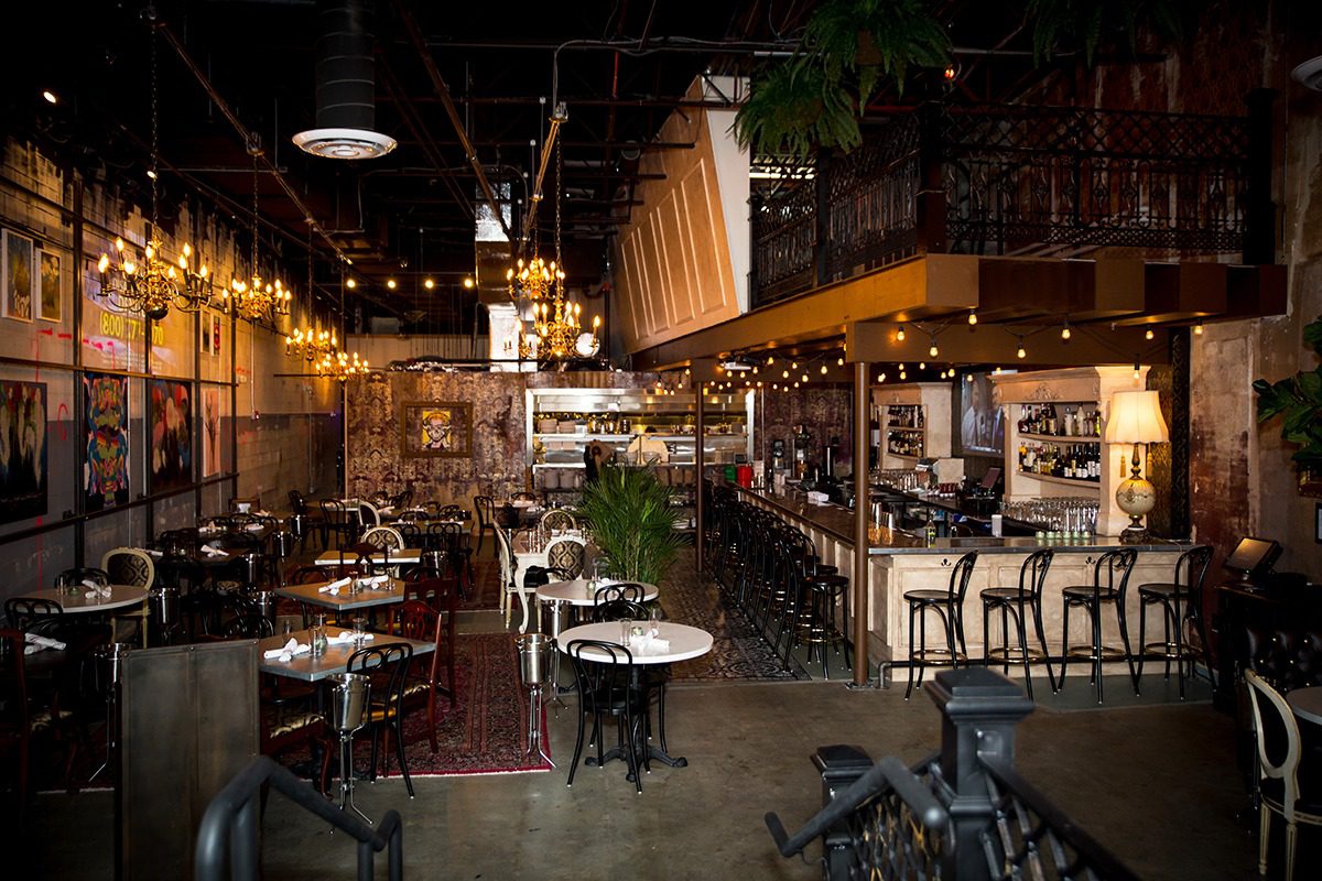 Cozy, warmly lit restaurant interior with elegant dining tables and bar seating.