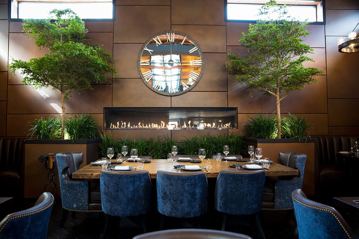 Elegant dining area with blue chairs and a large round mirror.