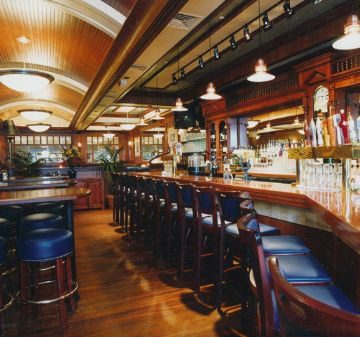 Cozy bar with wooden stools and warm lighting.