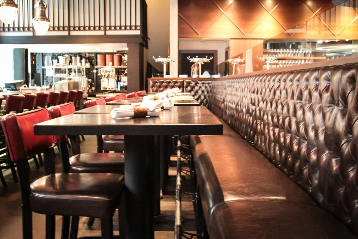 Cozy restaurant dining area with leather banquettes and wooden tables.