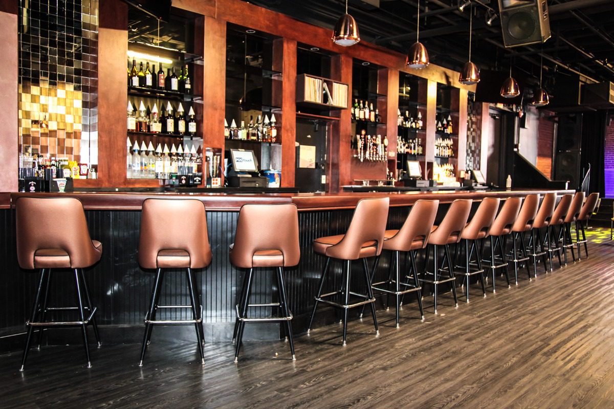 Empty bar stools lined up at a sleek, modern bar counter.