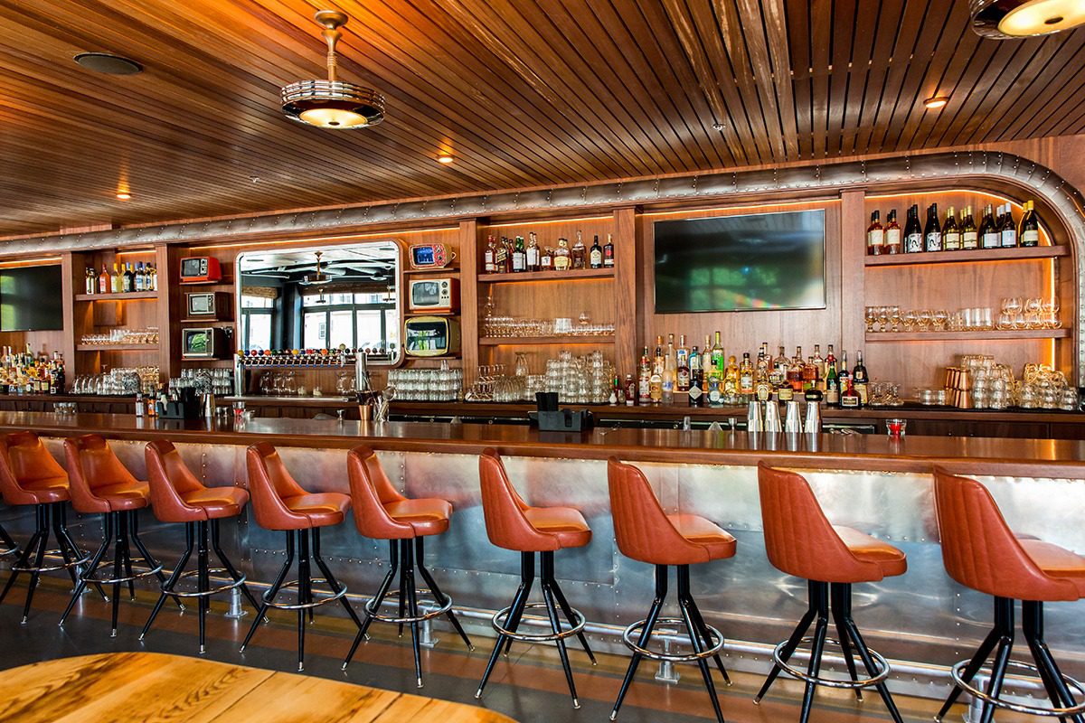 Cozy bar with wooden ceiling and orange leather stools.