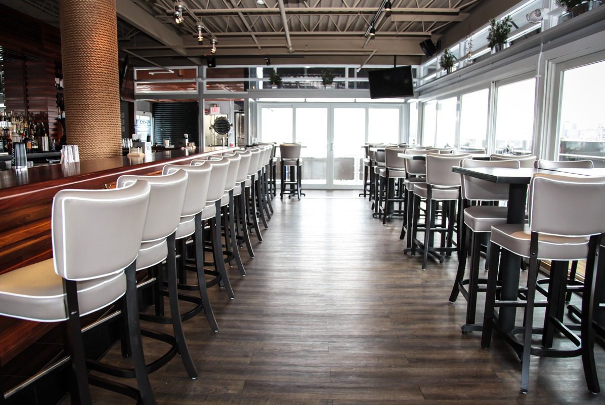 Empty modern bar with white chairs and wooden floor.