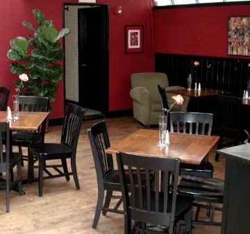 Cozy dining area with wooden tables and black chairs in a warmly decorated space.