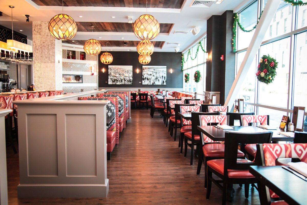 Elegant restaurant interior with red cushioned chairs and warm lighting.