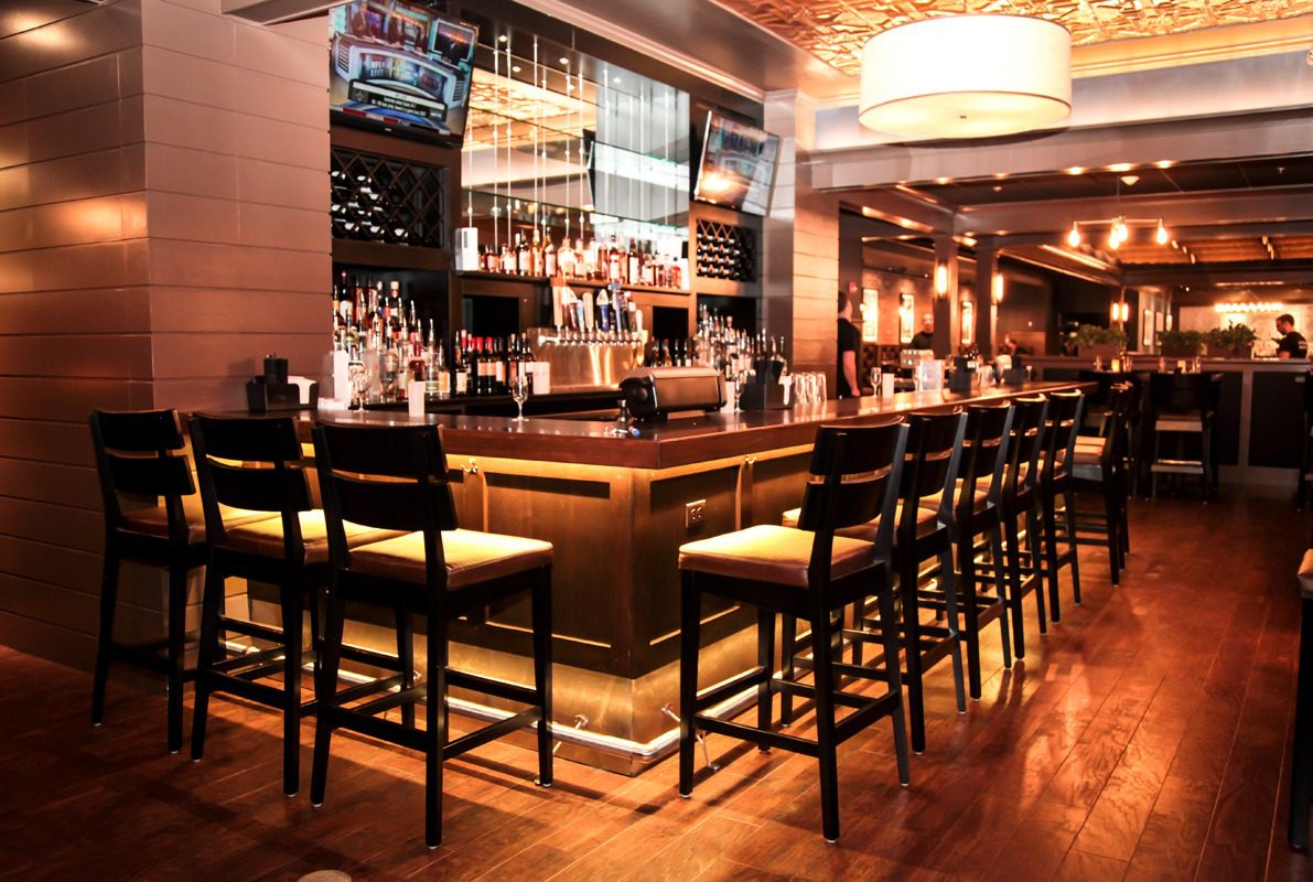 Cozy bar with wooden stools and warm lighting.